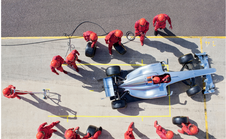 A professional race car pit crew works in perfect coordination, each member focused on their role -- changing tires, refueling, and fine-tuning the vehicle in seconds. The image illustrates what it means to be world class: clarity of roles, precise execution, and total commitment to team success, where preparation and discipline enable peak performance when it matters most.